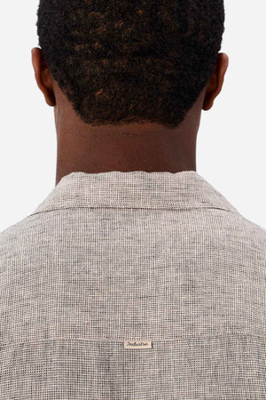 A person with short, curly hair is shown from behind wearing a light gray Industrie The Melrose Short Sleeve Shirt featuring a small tag at the upper back, set against a plain white background.