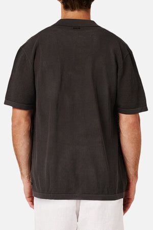 Someone is shown from the back wearing the Industrie The Nanterre Short Sleeve Shirt in dark gray, which has a loose, oversized fit, paired with light-colored pants against a plain white background.