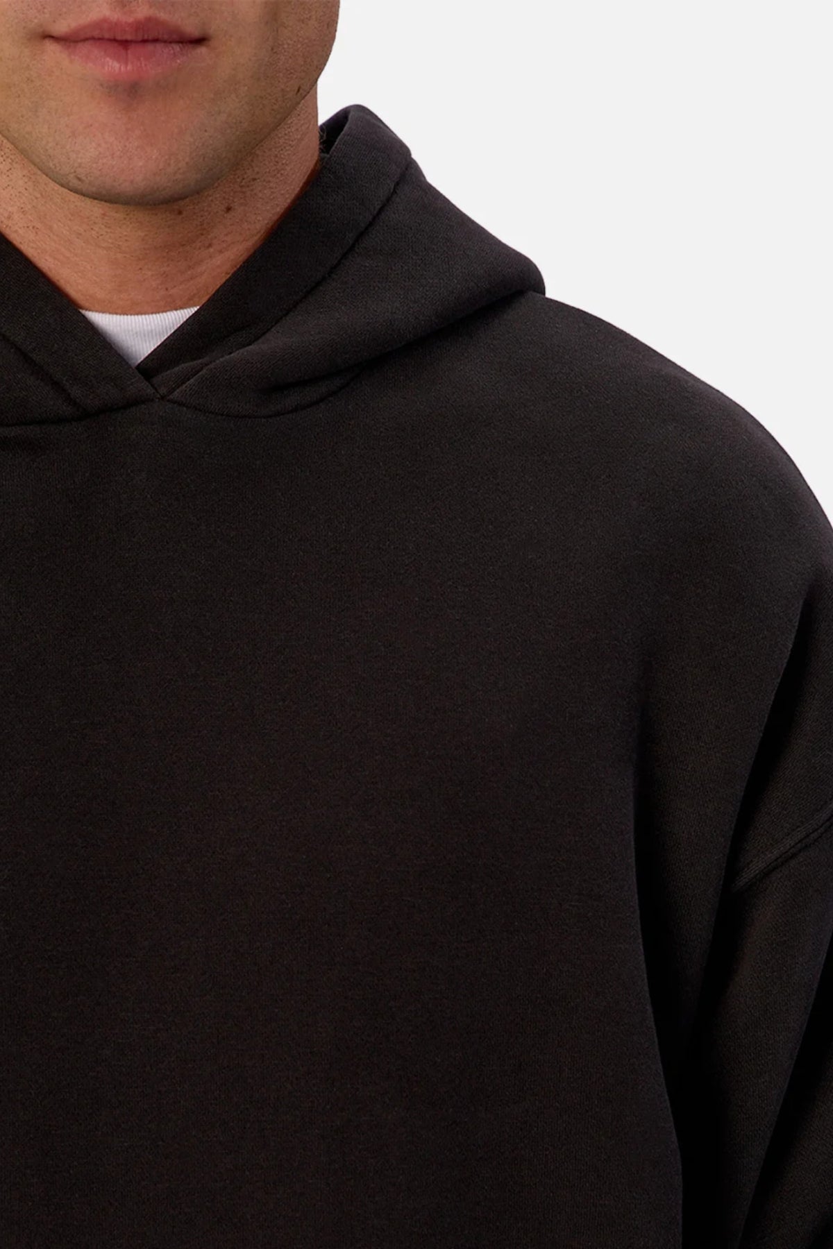 A close-up of a person wearing the Industrie The New Del Sur Fleece Hoodie in black over a white shirt, showing only the lower half of their face and upper torso against a plain background.