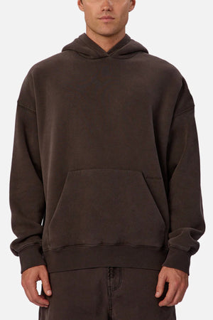 A man wears the Industrie The New Del Sur Fleece Hoodie in dark brown, featuring a relaxed fit, long sleeves, front pocket, and cotton-polyester fleece. His hands are by his sides against a plain white background.