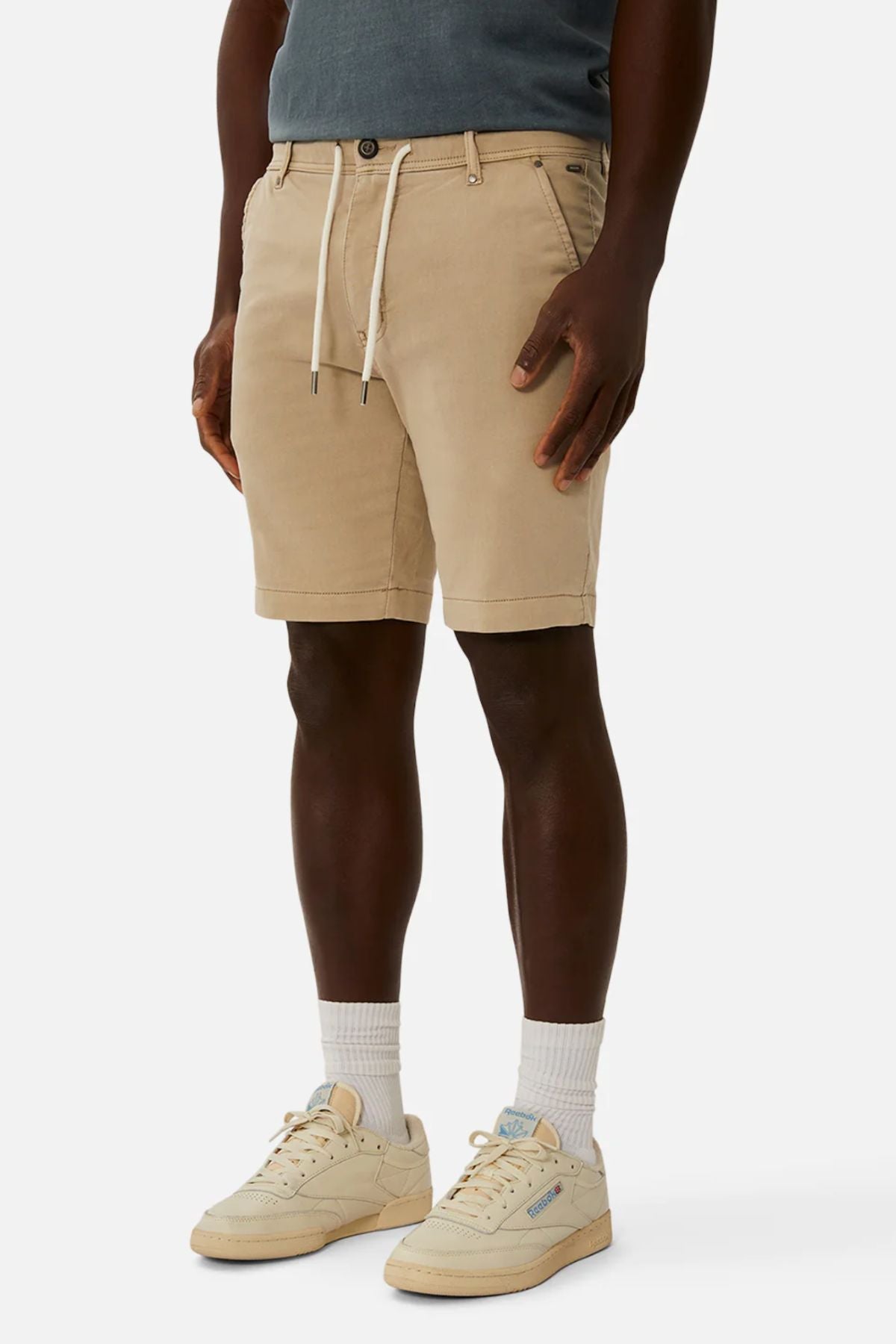 Wearing Industrie The New Drifter Cuba Shorts in beige with a white drawstring, paired with a teal shirt and beige sneakers with matching socks, the person stands confidently against a plain white background.