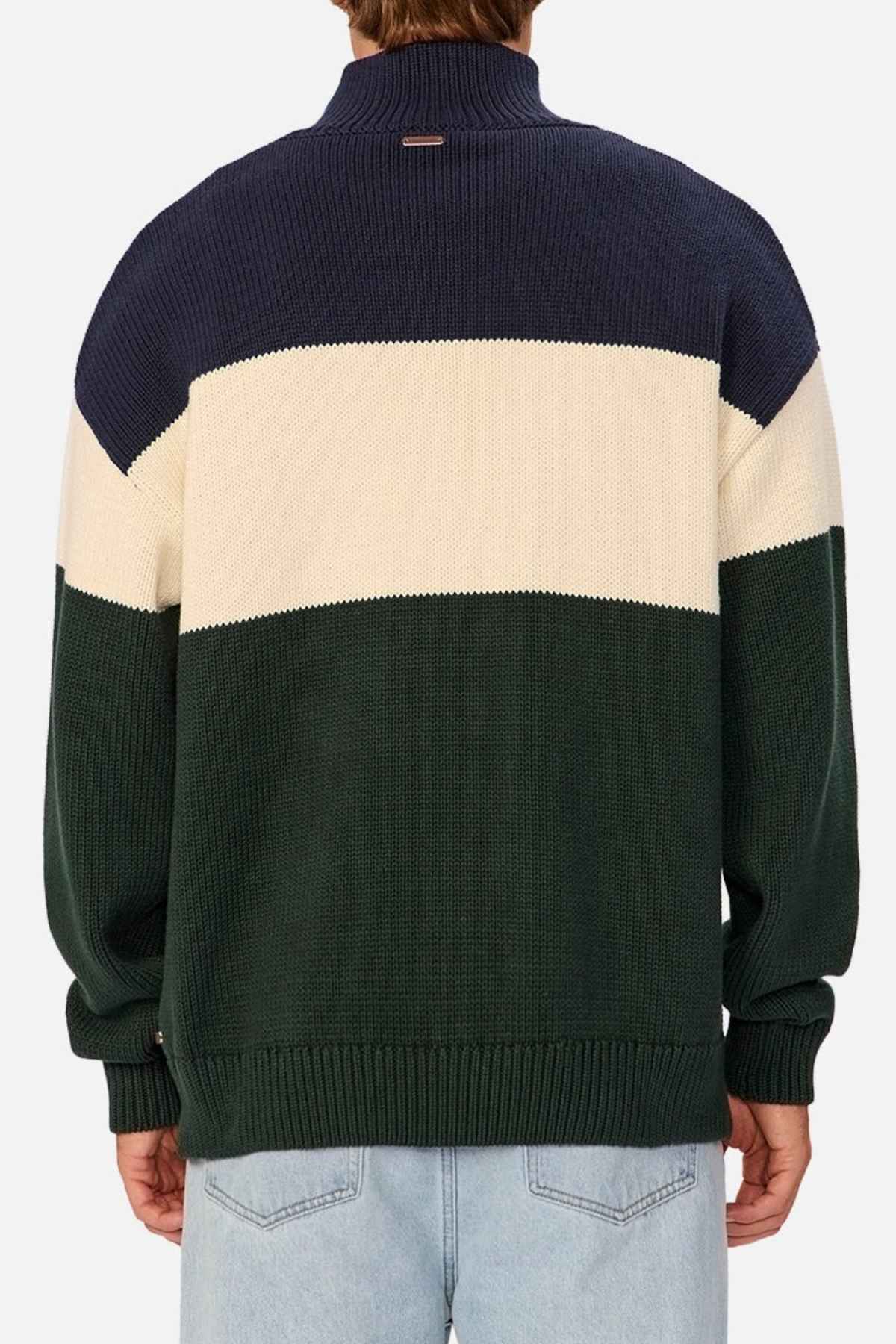 Rear view of a person wearing the Industrie The Osbourne Zip Neck Knit, a timeless piece adorned with navy blue, white, and green horizontal stripes. This 100% cotton sweater features a ribbed texture, long sleeves, and a high collar. The person is also sporting light blue jeans.
