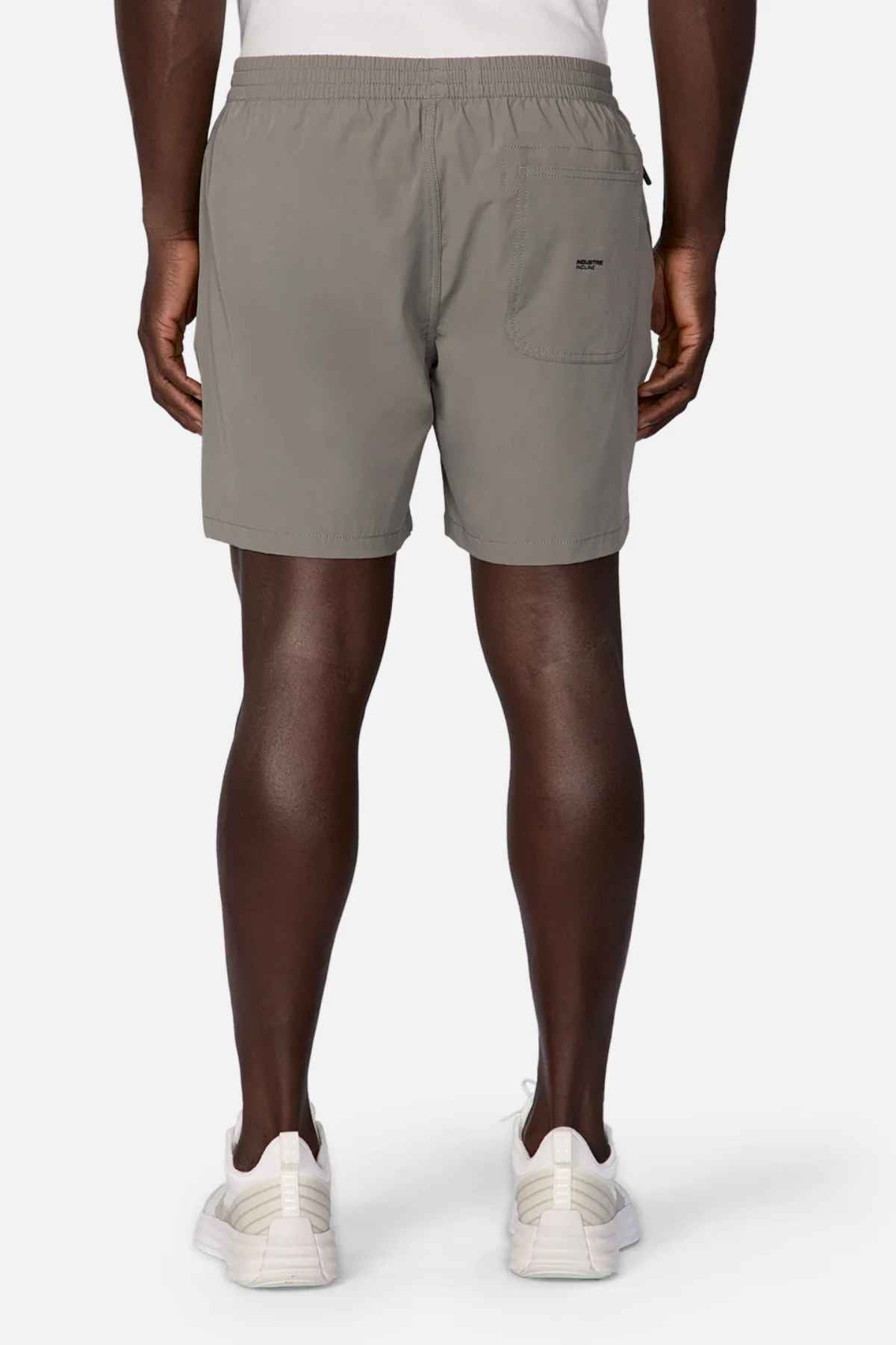 A person is seen from the back wearing Industrie The Owens Short, gray athletic shorts with an elasticized waistband and white sneakers. These above-knee-length shorts have a small pocket on one side and are made of quick-drying fabric against a plain white background.