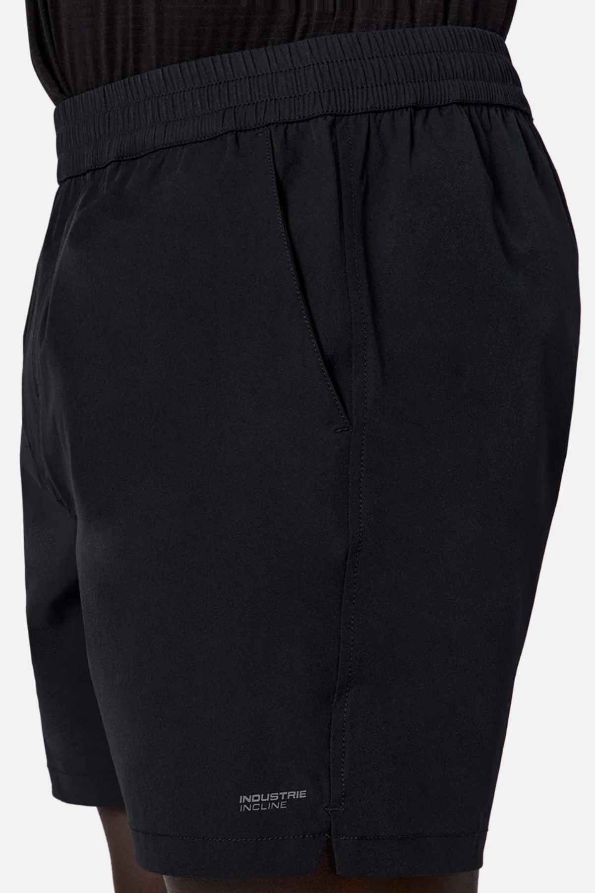 A person wearing 'The Owens Short' by Industrie—stylish black athletic shorts made from quick-drying fabric. They include an elasticised waistband, two side pockets, and subtle "INDUSTRIE INCLINE" branding near the hem.