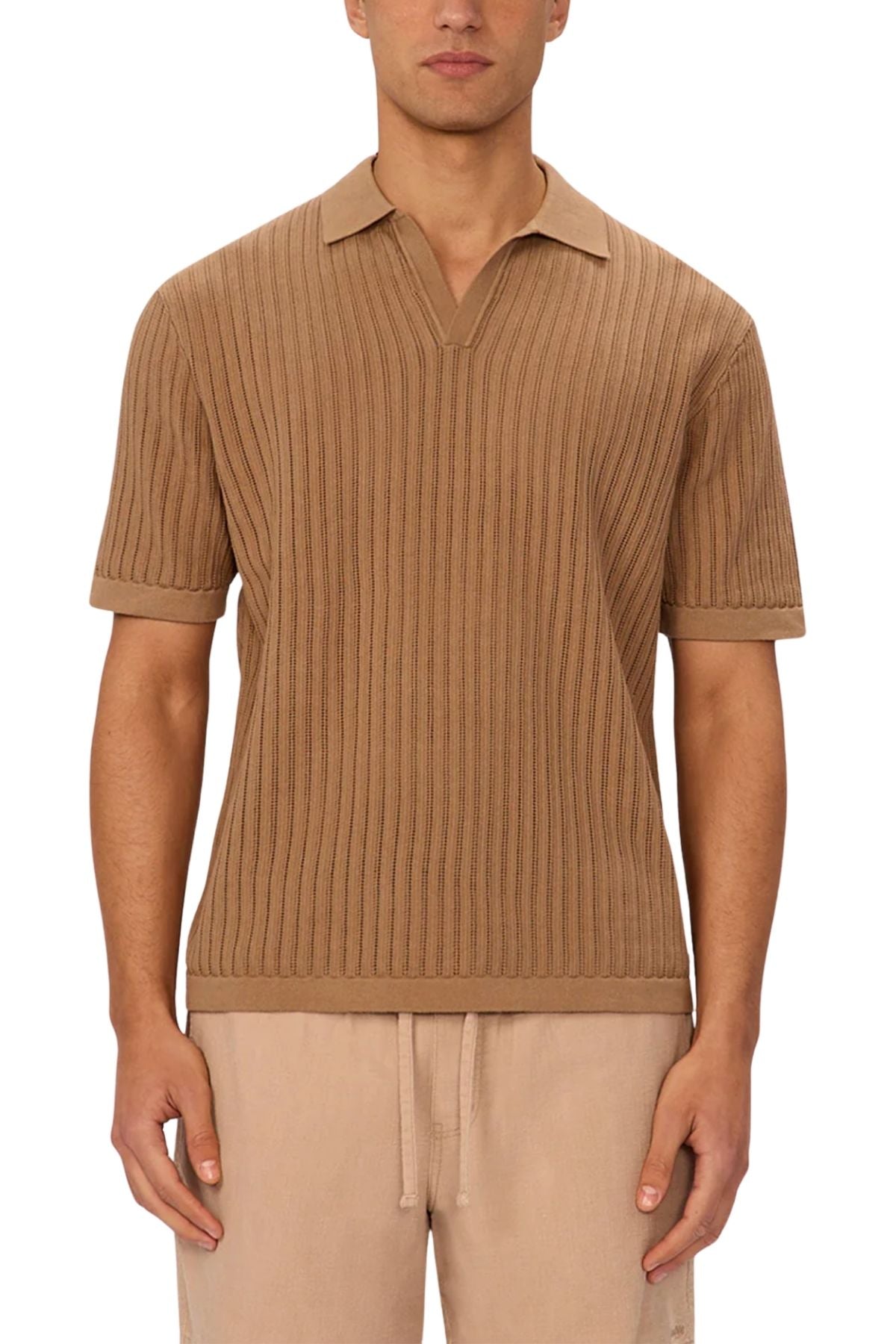 A man wears the Industrie The Poolside Polo, a short-sleeve ribbed tan cotton knit shirt with split neckline, paired with light beige drawstring pants. Its textured pattern and relaxed fit make it ideal for casual wear; his face is partly hidden.