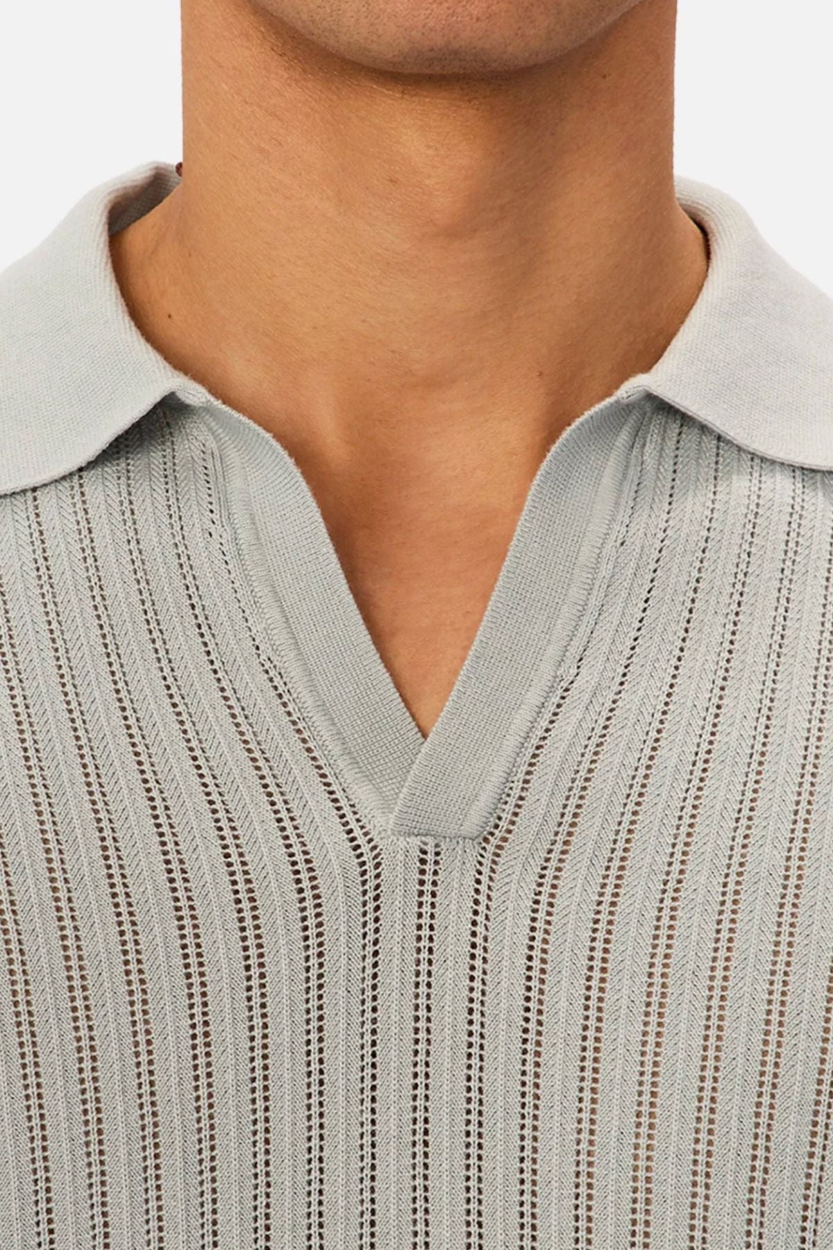 Close-up of a person wearing the Industrie The Poolside Polo in light gray, featuring short sleeves, a split V-neck collar, and vertical open-knit stripes. The image focuses on the upper chest and neck, ideal for casual style.