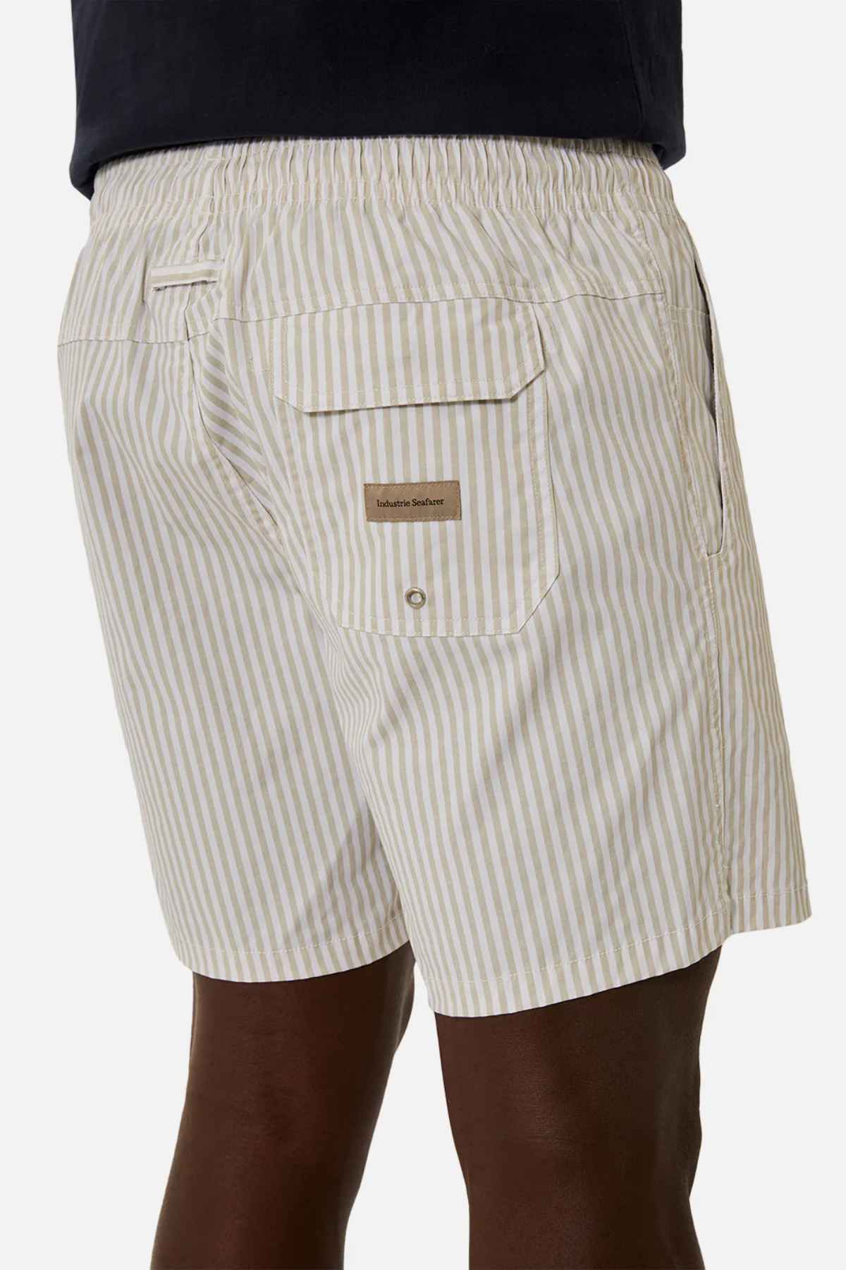 An individual is wearing Industrie The Princeton Bahama Shorts in a light color, featuring vertical stripes and an elastic waistband. These shorts are detailed with a back pocket adorned with a button flap, subtly showcasing the Industrie branding.