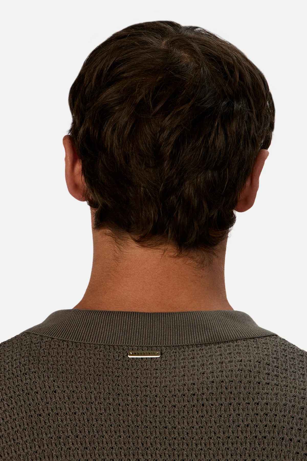 Back view of a person with short brown hair, wearing the Industrie The Sevona Short Sleeve Shirt. A small metallic label embellishes the upper back, subtly indicating Sevona's touch. The plain light background perfectly complements this stylish summer wardrobe essential.