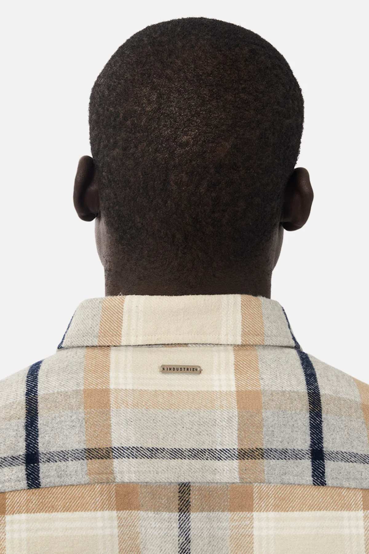 Rear view of a person with short hair wearing the Industrie The Somerville Shirt in plaid beige, gray, and blue. A small Industrie tag features on top against a plain white background.