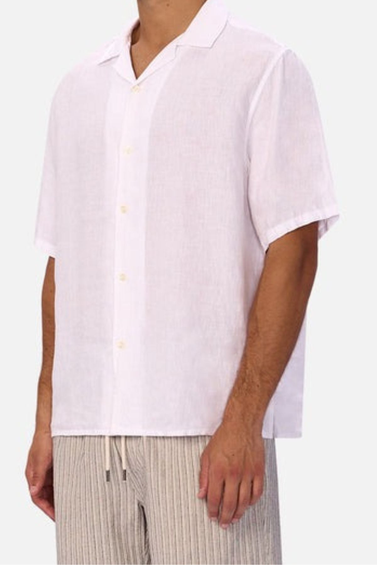 A man wears the Industrie The St Martins Short Sleeve Shirt with light, striped drawstring pants. Both pieces are loose and breathable, creating a relaxed look. The image is cropped from the neck down.