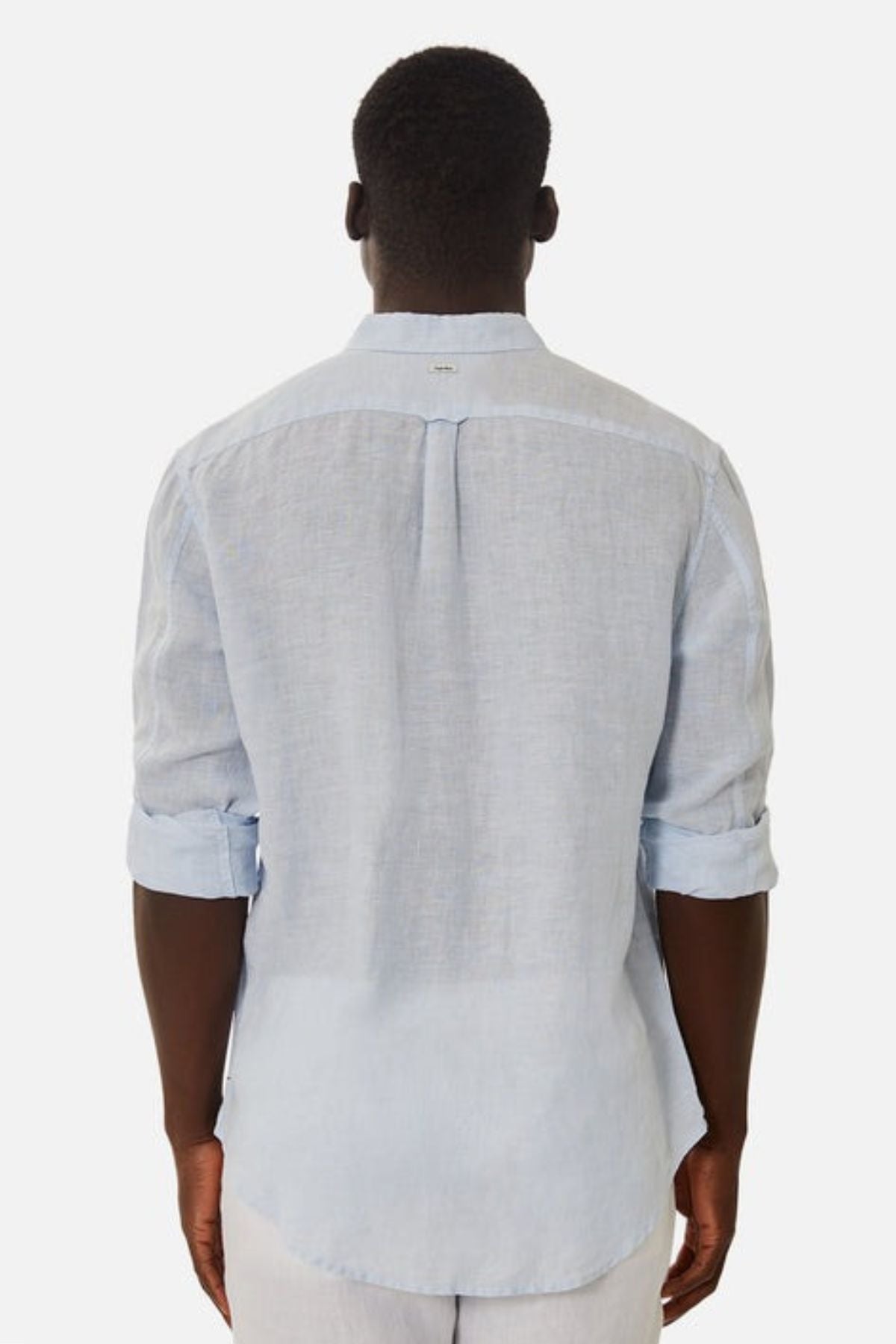 A person is showcasing the effortless elegance of the Industrie The Tennyson Linen Blend Shirt, a versatile light blue garment with rolled-up sleeves. Featuring a back pleat, this lightweight shirt provides both comfort and style as they face away from the camera against a plain white background.