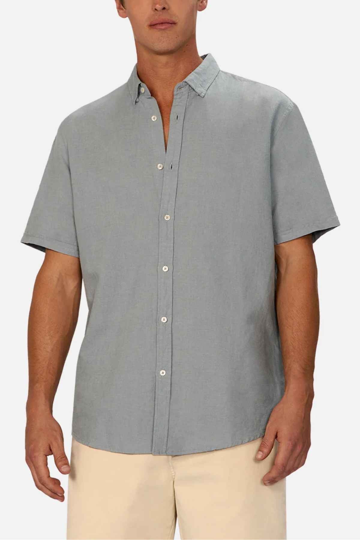 A man is wearing the Industrie The Tennyson Linen Blend Short Sleeve Shirt in light gray, paired with beige pants against a plain white background, showcasing summertime comfort.