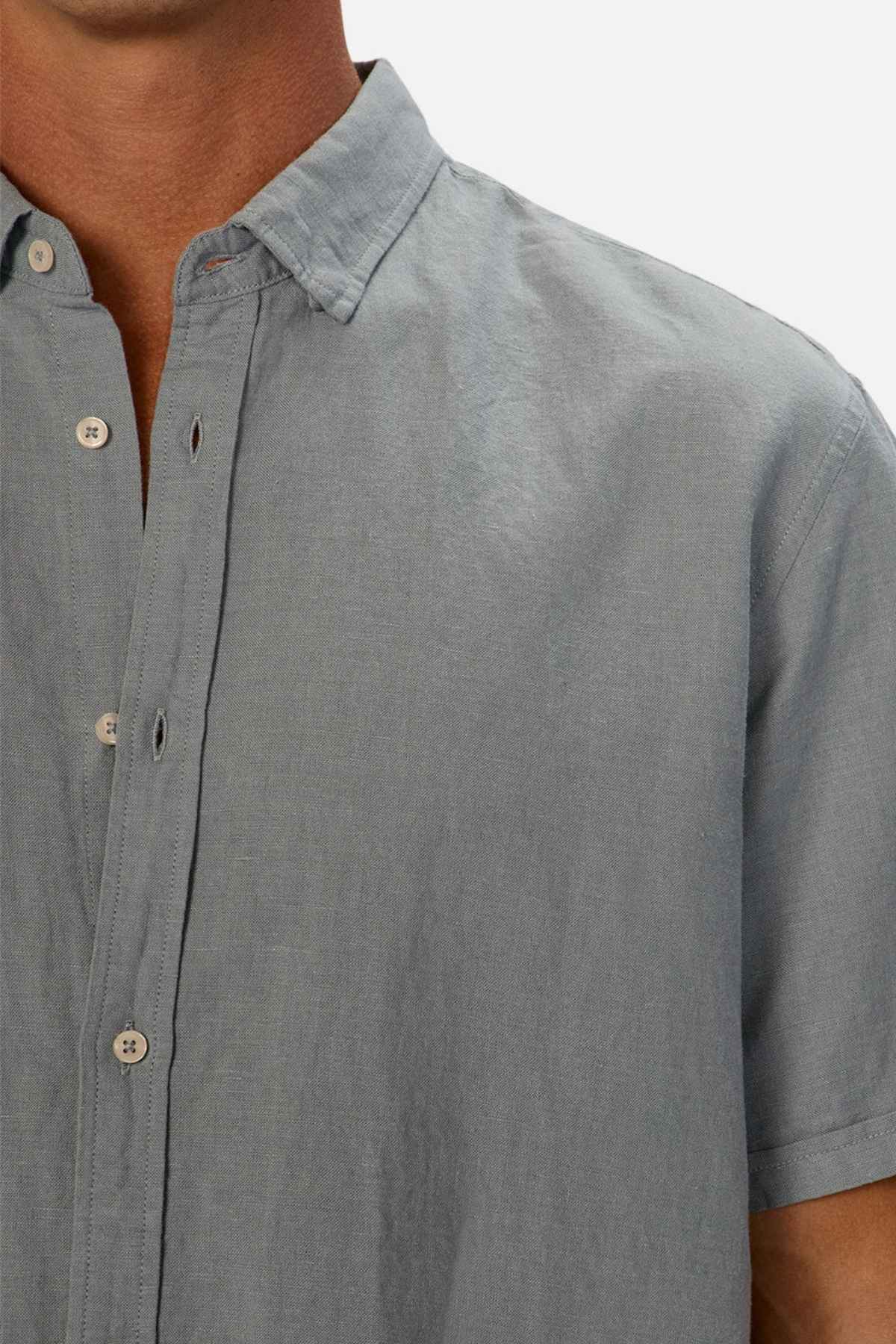 A person is wearing the Industrie The Tennyson Linen Blend Short Sleeve Shirt in light grey, with the top buttons undone, shown from the shoulders to mid-torso against a plain background, capturing an essence of summertime comfort.