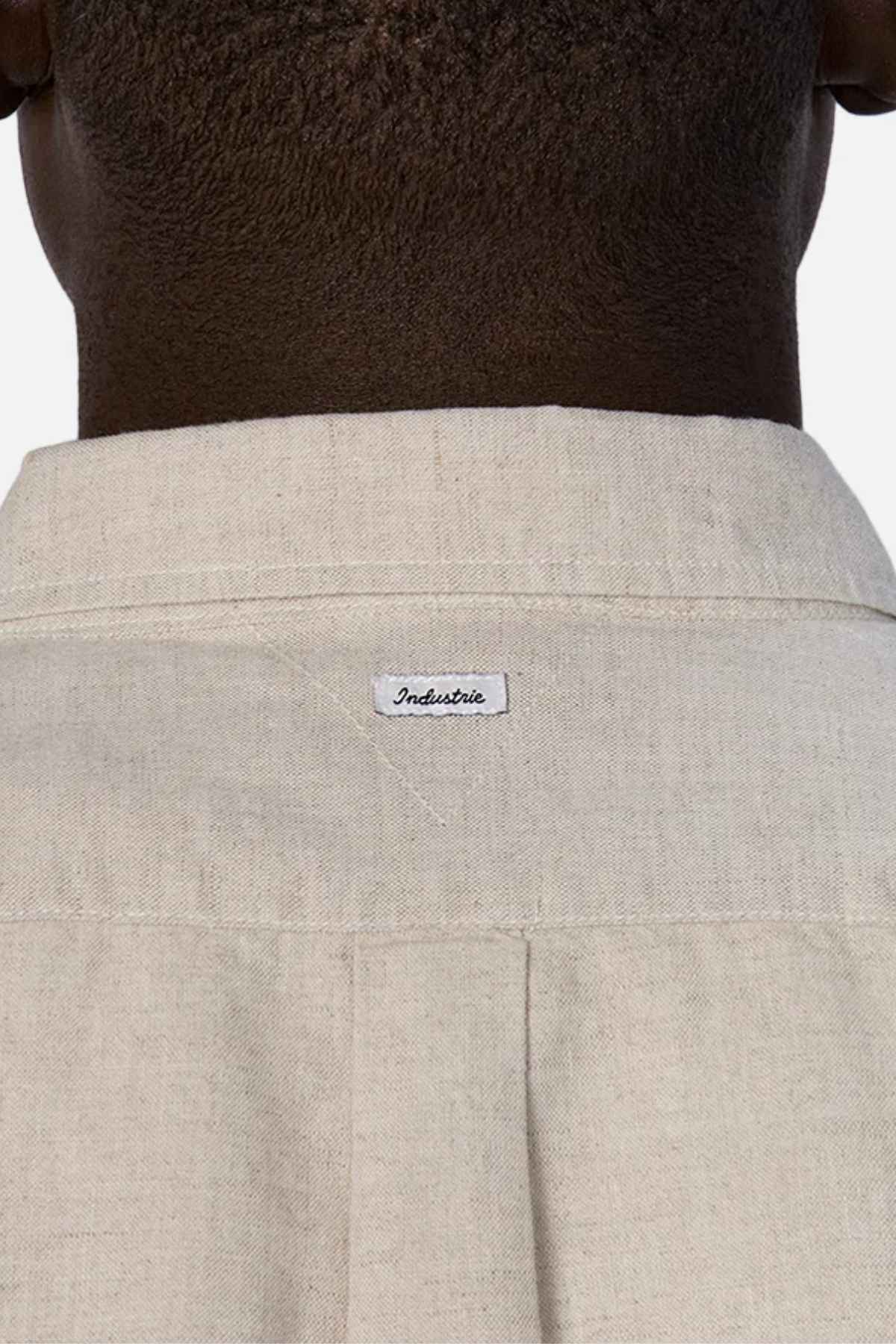 Close-up of the back of a person's neck and shoulders, wearing the Industrie The Tennyson Linen Blend Short Sleeve Shirt in light beige, which exudes summertime comfort, with a small label reading "Industrie.