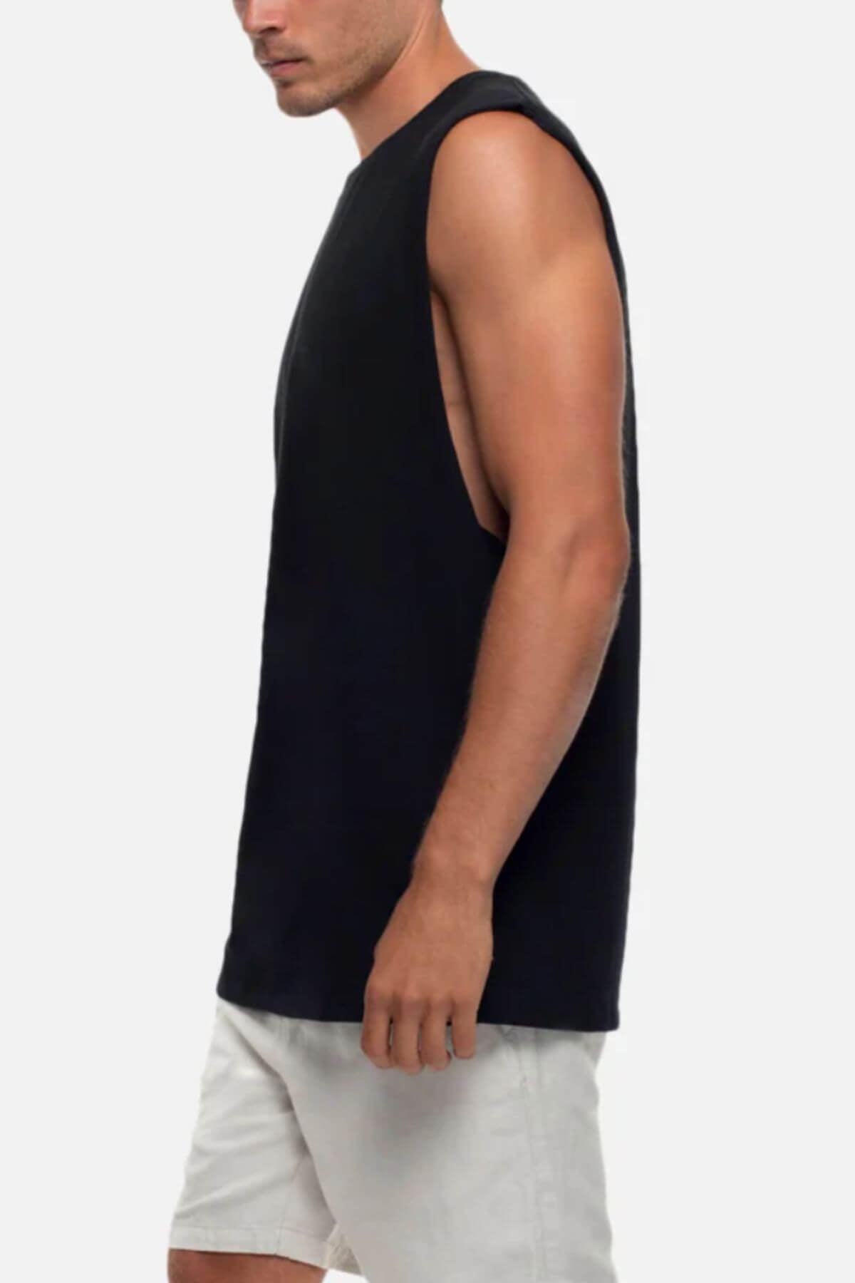 Wearing the Industrie The Triple G Sleeveless Tee in relaxed fit black and light shorts, a person stands sideways on a plain background with their face not visible.