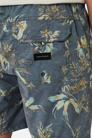 Close-up of the back of a person wearing Industrie The Viloria Bahama Short—blue floral swim shorts with an elastic waistband, flap pocket, "Industrie Seafare" black label, and tropical bird and leaf designs.
