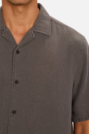 A close-up of a person wearing the Industrie The Washed Menorca Short Sleeve Shirt, featuring a textured cotton blend and spread collar; only their lower face, neck, and upper torso are shown.