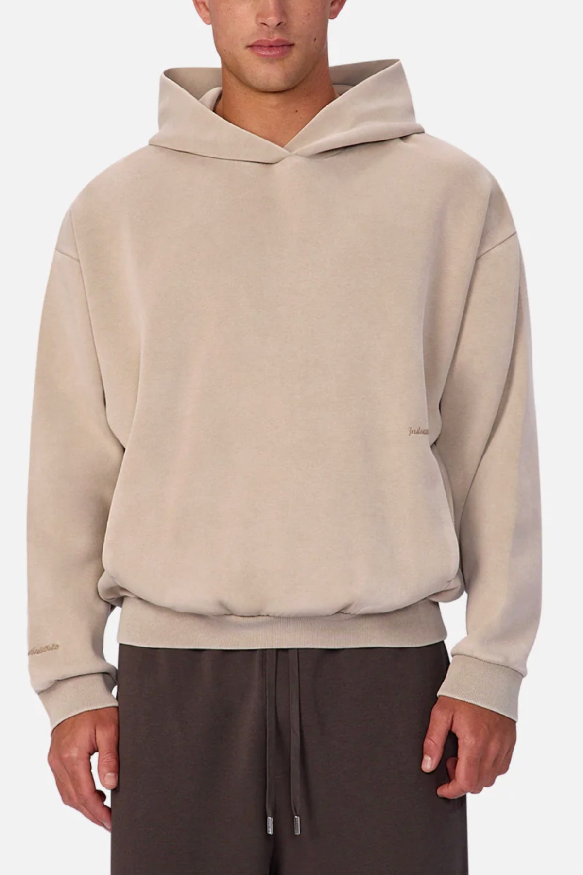 A person wearing the Industrie The Washed Tech Hood in light beige with long sleeves and dark brown drawstring pants stands against a white background. The hoodie offers a relaxed fit and modern style, perfect for casual everyday wear.