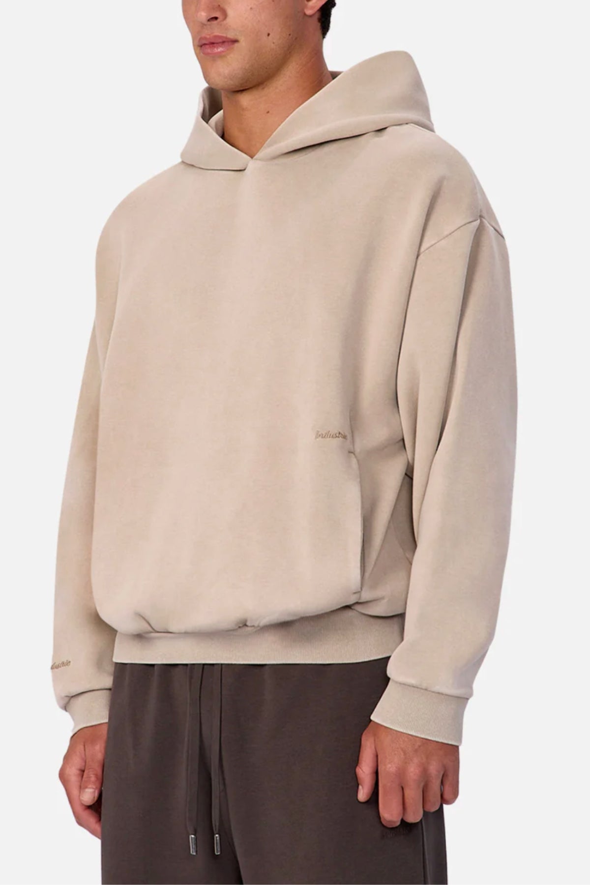 A person wearing the Industrie The Washed Tech Hood in beige with dropped shoulders and brown drawstring pants against a white background—a relaxed, casual everyday look.
