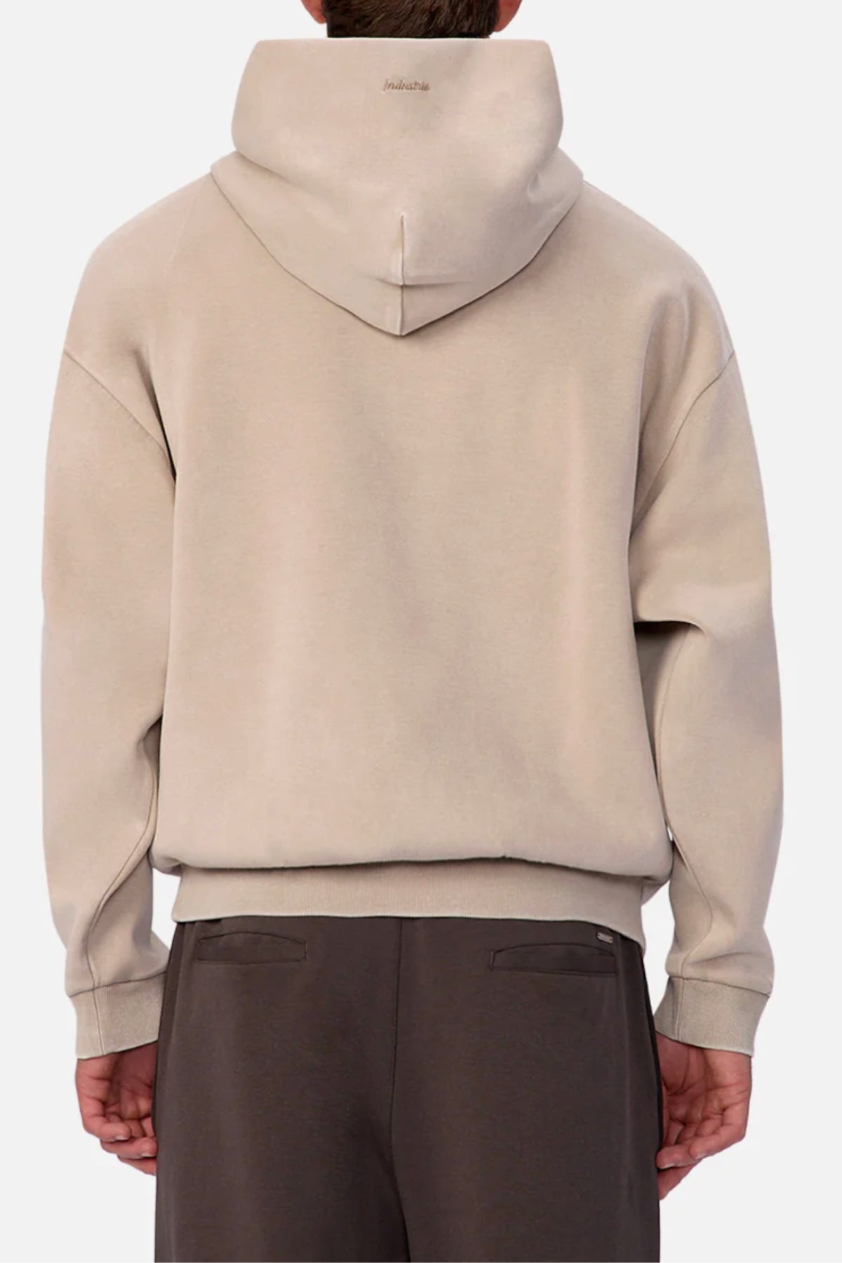 A person wears the Industrie The Washed Tech Hood in beige with the hood up, styled with dark brown pants against a plain light background—ideal for casual everyday looks.