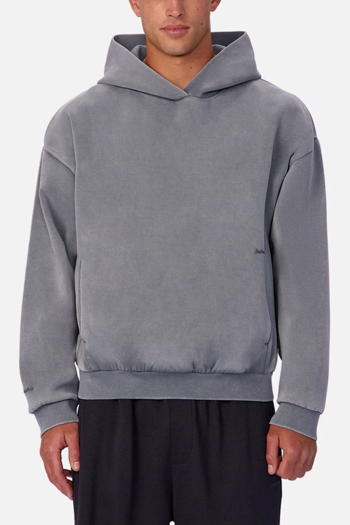 Someone wears the Industrie The Washed Tech Hood, a loose-fitting gray sweatshirt with long sleeves, styled casually with black pants against a plain light background—perfect for layering in everyday looks.