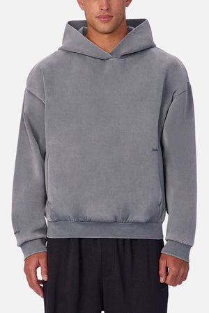 Someone wears the Industrie The Washed Tech Hood, a loose-fitting gray sweatshirt with long sleeves, styled casually with black pants against a plain light background—perfect for layering in everyday looks.