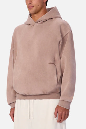 A person wearing the Industrie The Washed Tech Hood in light brown, featuring a loose fit and front pocket, paired with white drawstring pants—ideal for fans of contemporary casual style.
