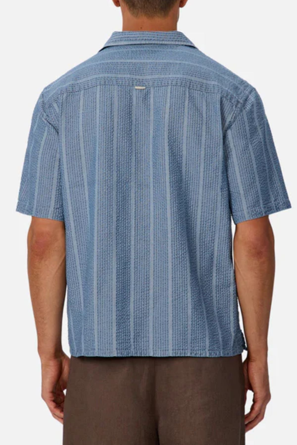 A person is shown from the back against a plain background, wearing an Industrie The Kimridge Short Sleeve Shirt with blue patterns and brown pants.