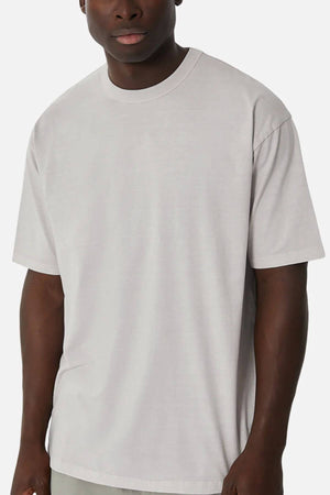 Someone wears the Industrie The Del Sur Tee, an oversized fit T-shirt in light gray made from 100% cotton, featuring a crew neckline and no visible logos or designs, standing against a plain white background.