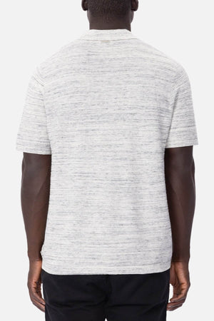 The back view showcases a man in a light gray, short-sleeve T-shirt with a subtle texture and horizontal pattern, complemented by dark pants. The plain white background accentuates his effortless style, evoking the essence of Industrie The Lorenzo Polo.