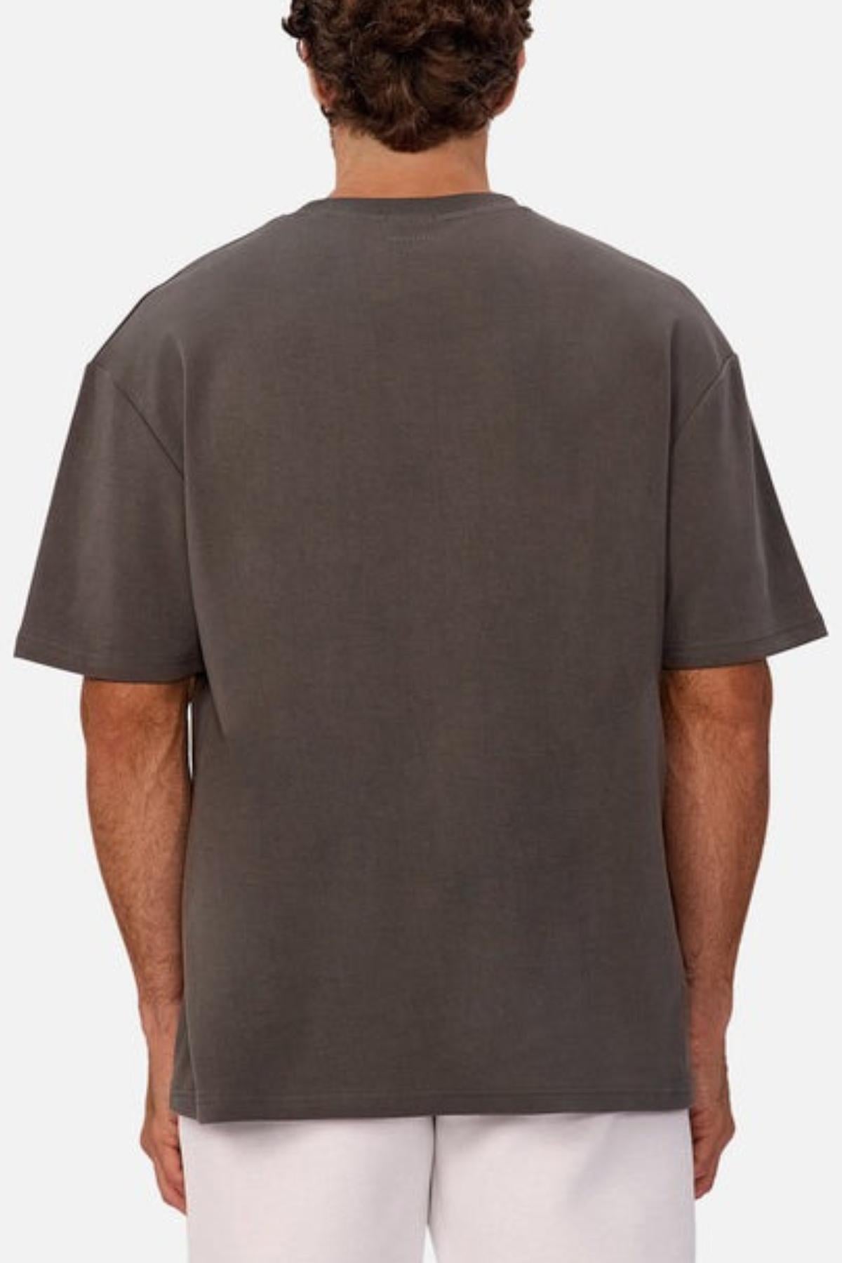 A person with curly hair is shown from the back, wearing an Industrie The Newport Tee and light-colored shorts against a plain, light background.