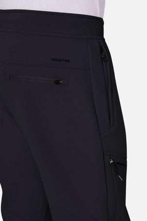 Close-up of a person in Industrie The Tech Armoured Track Pant, featuring multiple combat pockets and "INDUSTRIE" near the waistband, paired with a tucked-in white shirt.