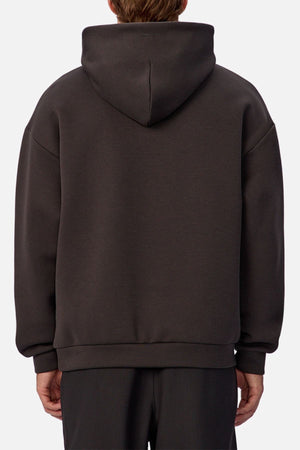 Someone is seen from the back wearing the Industrie The Tech Del Sur Hoodie, a loose-fitting, dark gray pullover with the hood up, against a plain light background.