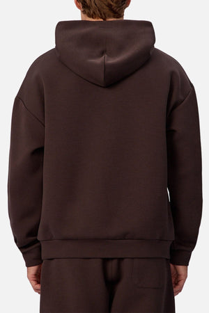 A person wearing an Industrie The Tech Del Sur Hoodie in dark brown, paired with matching pants and viewed from the back against a plain light background, highlights the hoodie's sleek design and breathable fabric.