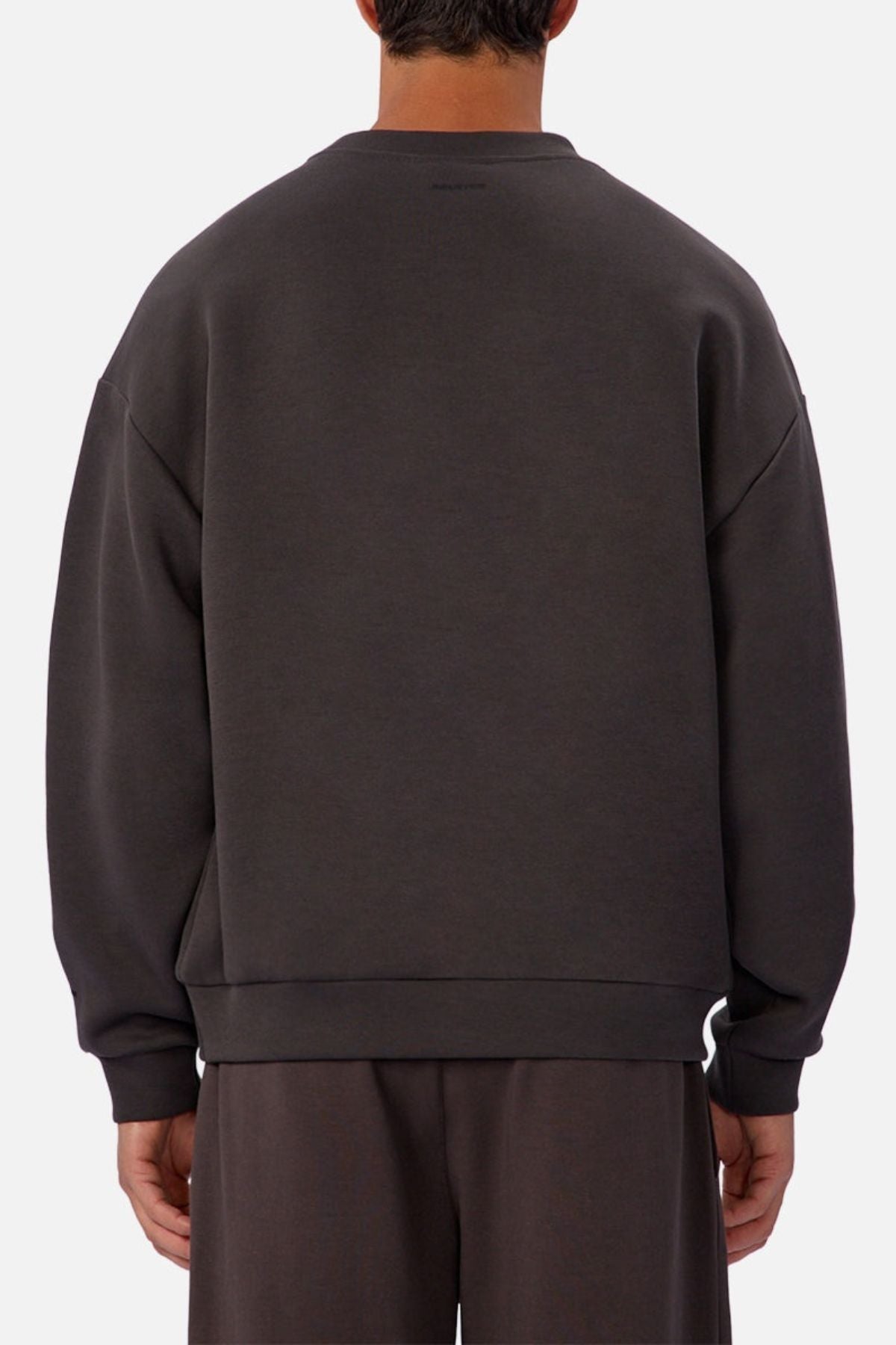 A person is shown from behind in a loose-fitting, dark gray Industrie The Tech Del Sur Sweat and matching pants. The light background emphasizes its athletic design crafted for an active lifestyle.