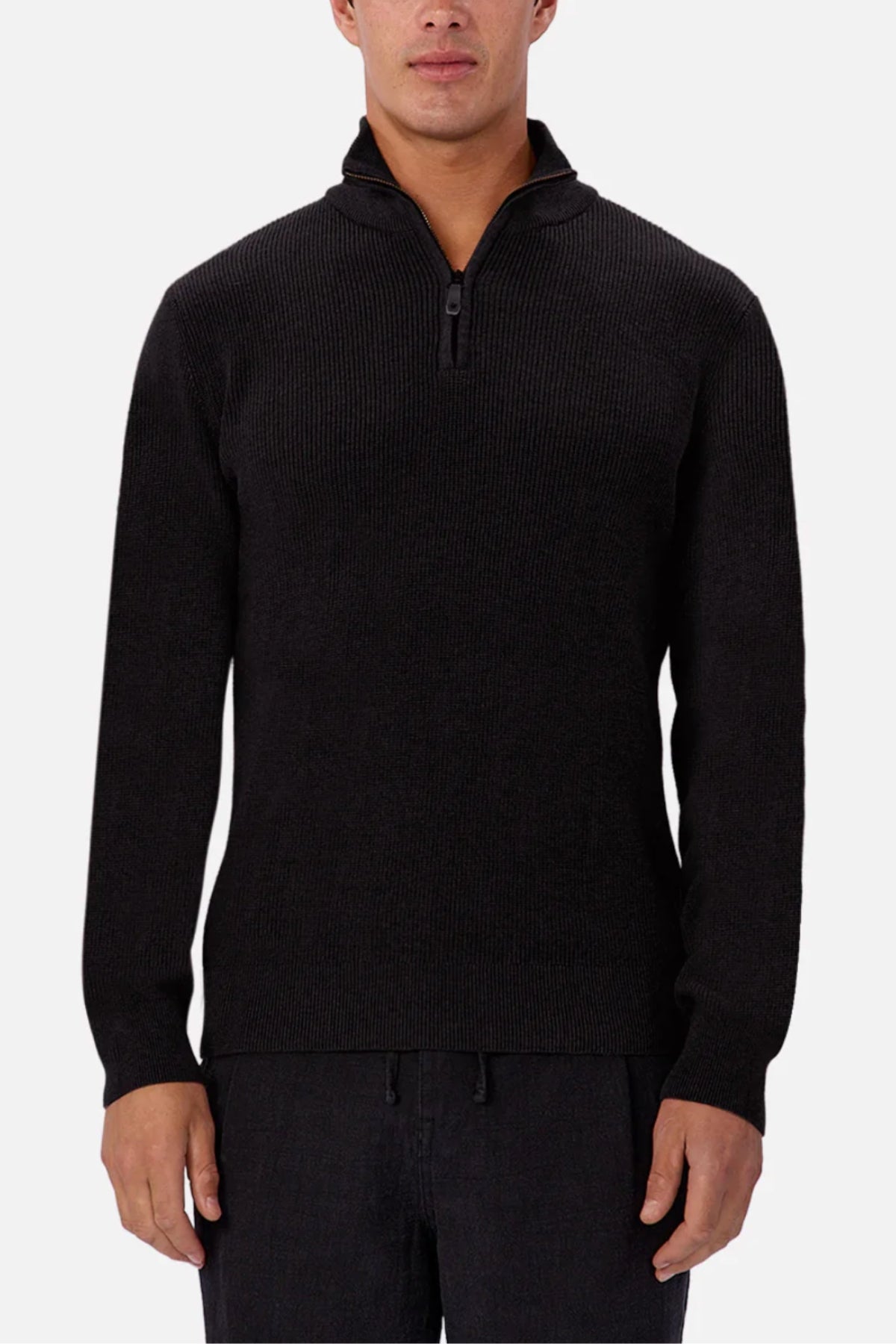 A man wears the Industrie The New England Zip Neck Knit—a black, ribbed, 100% cotton sweater with a standing collar and zip neck—standing against a plain white background.