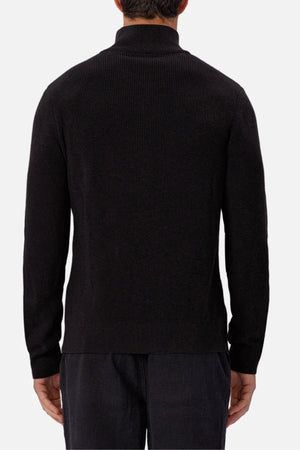 A person is shown from the back wearing the Industrie The New England Zip Neck Knit, a black long-sleeve sweater with a high collar, paired with dark pants against a plain white background.