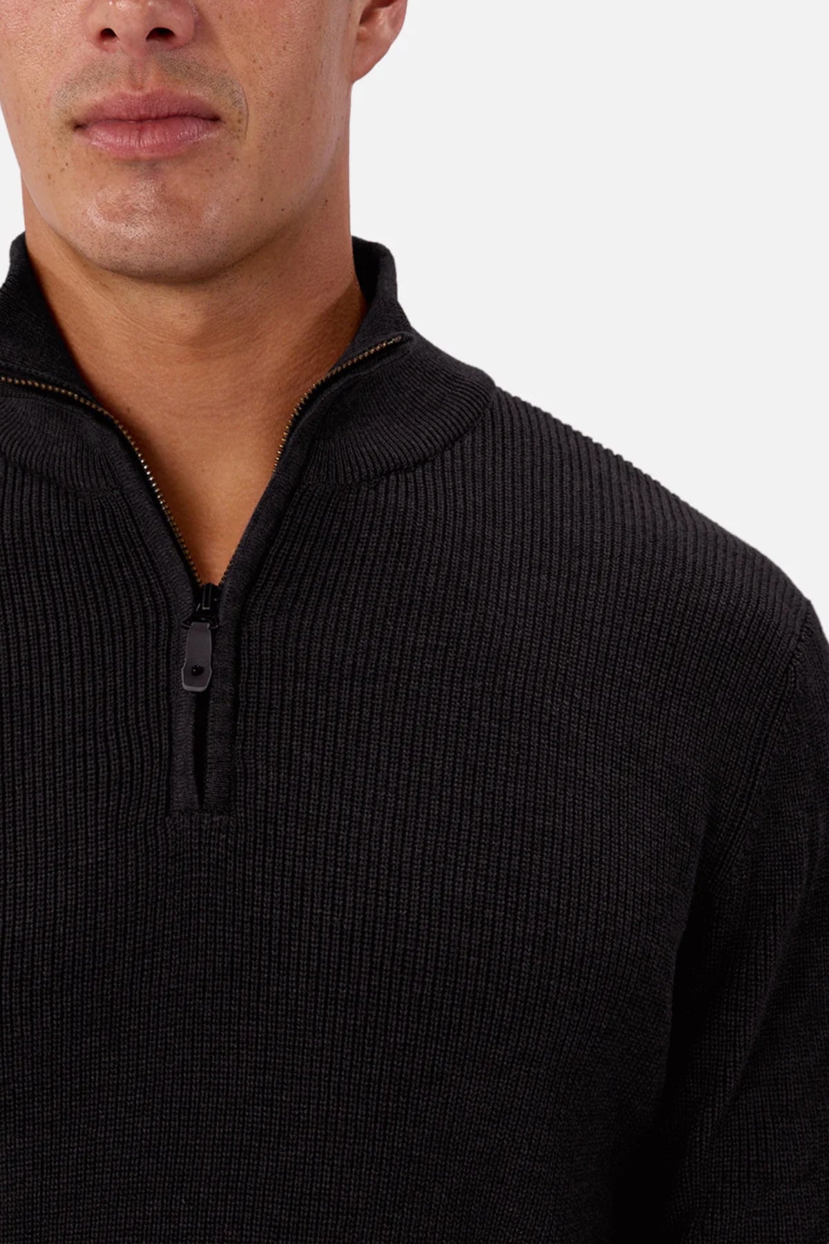 A man models the Industrie The New England Zip Neck Knit, a black 100% cotton sweater. The image highlights the top half and textured zip neck against a plain, light background, with his face partly visible.