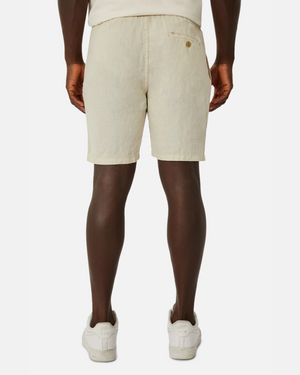 Rear view of a person wearing beige Industrie The Marina Linen Short and white sneakers on a white background. The pure linen shorts feature a back pocket with button. They're paired with a light-colored shirt.