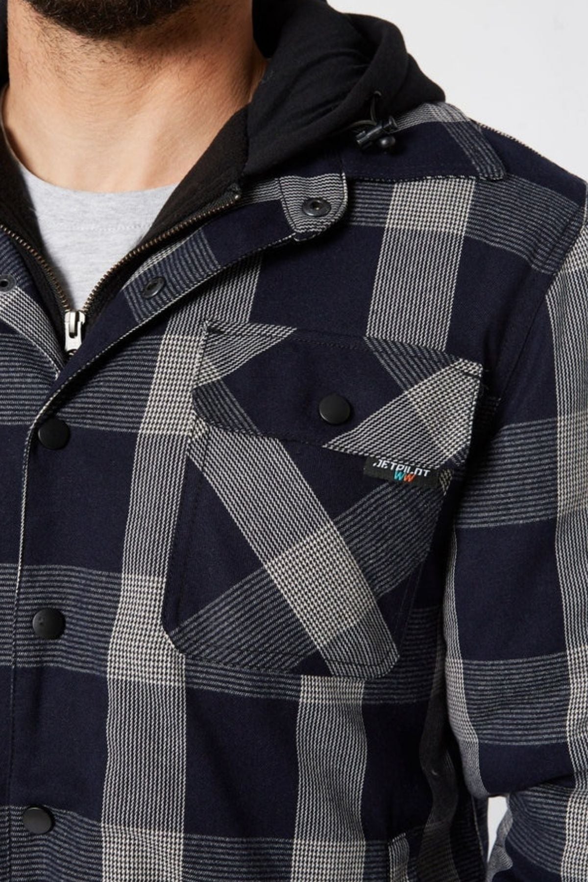 Someone is wearing a dark blue and gray Jetpilot Quilted Flannel Jacket with black buttons, a flap chest pocket, and a small embroidered logo, layered over a gray shirt and black hoodie.