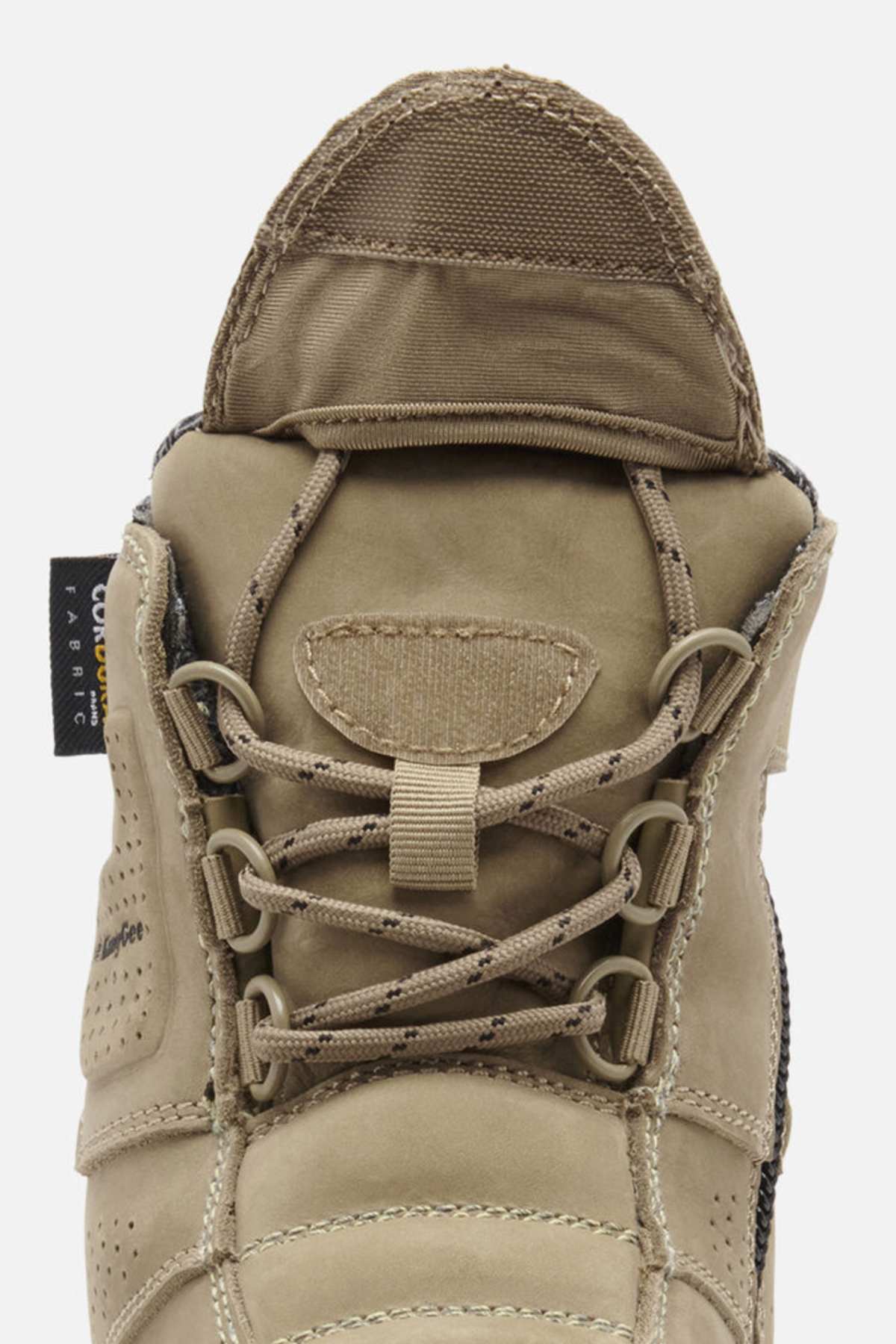 A close-up of the tan King Gee Bennu Pro 6 Work Boot highlights its laces, tongue, side fabric tag, and slip-resistant outsole as the boot faces upward.