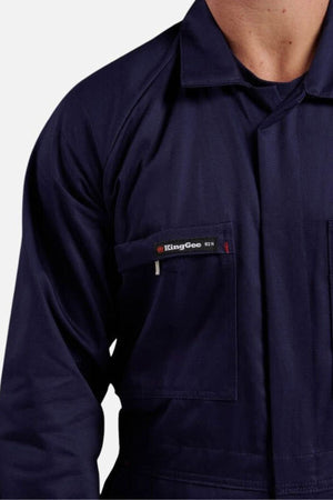 A person wears a dark blue King Gee Combination Drill Overall shirt. The image highlights the upper torso, focusing on the chest pocket with the KingGee logo and part of the collar, set against a plain light background.
