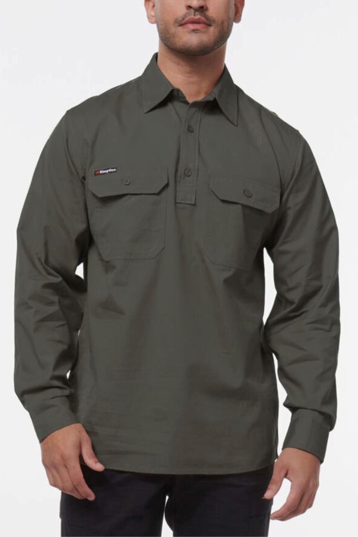 A man wearing a King Gee Workcool Vented Closed Front Shirt in dark green and black pants stands against a plain white background.