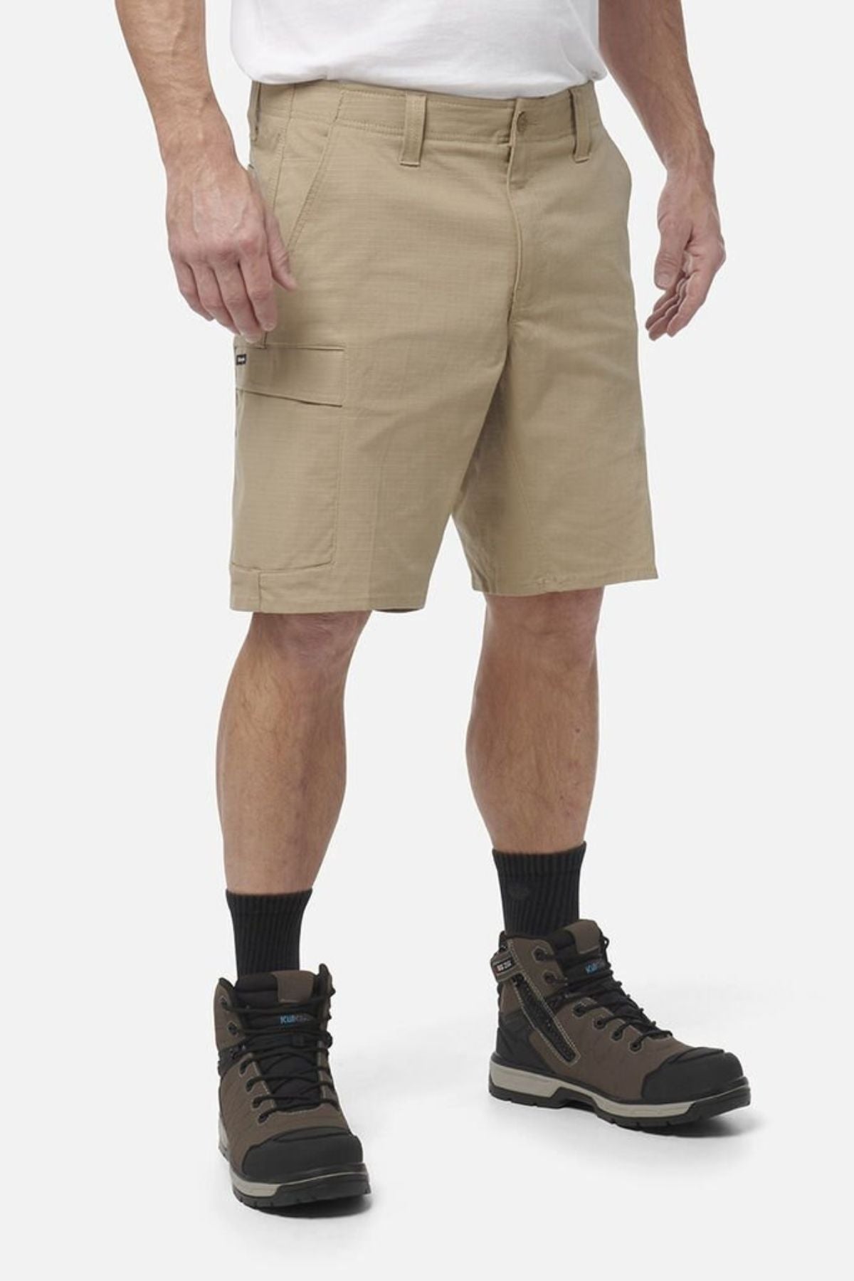 A person wearing King Gee Workcool Pro Shorts in khaki, a white shirt, black socks, and brown hiking boots stands against a plain white background.