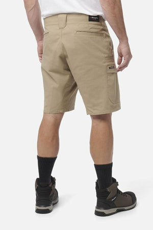A man wearing King Gee Workcool Pro Shorts, a white shirt, black crew socks, and brown work boots stands with his back to the camera against a plain white background.