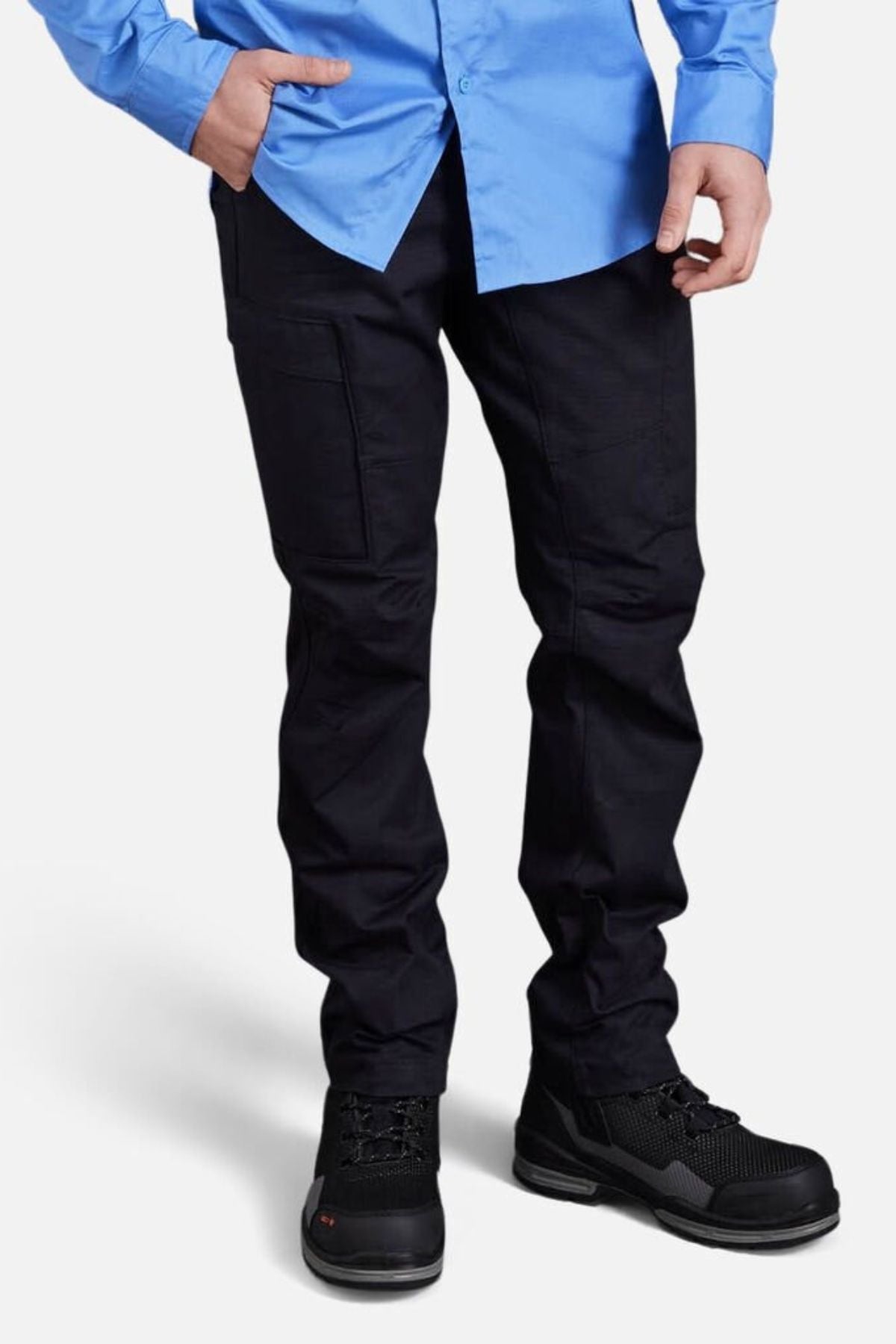 A person stands against a plain white background, cropped at the shoulders, wearing a bright blue button-up shirt, black King Gee Workcool Pro Stretch Cargo Pants with multifunctional pockets, and black work shoes.