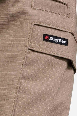 Close-up of a tan pocket on the King Gee Workcool Pro Stretch Cargo Pant, showing a black "King Gee" label with a red crown and white text. The stretch ripstop fabric has a subtle grid pattern.