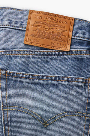 Close-up of the back of the Levis 555 Relaxed Straight Jean, showing blue denim, a brown Levi Strauss & Co. patch above the waistband, detailed stitching, and classic back pockets.