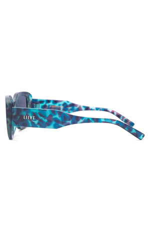 Side view of Liive Fringe Blue Meanie Sunglasses showcasing a multicolored blue and purple marbled finish with 90s-inspired rectangular frames. "LIIVE" is printed in white on the arm near the hinge.