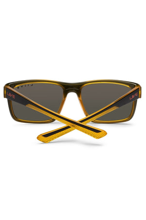 The Liive X Fairway X Sunglasses are rectangular casual shades with yellow frames, dark lenses, and crossed arms. "LIVE" is printed in red on the black arms near the hinges for a classic look.